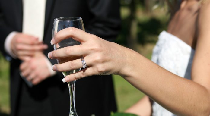 Una pareja de recién casados brindan con una copa de vino