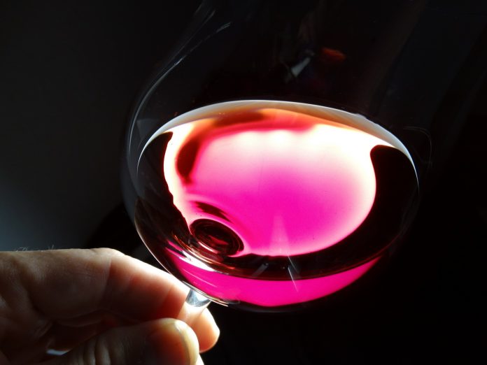 Una copa inclinada de vino rosado